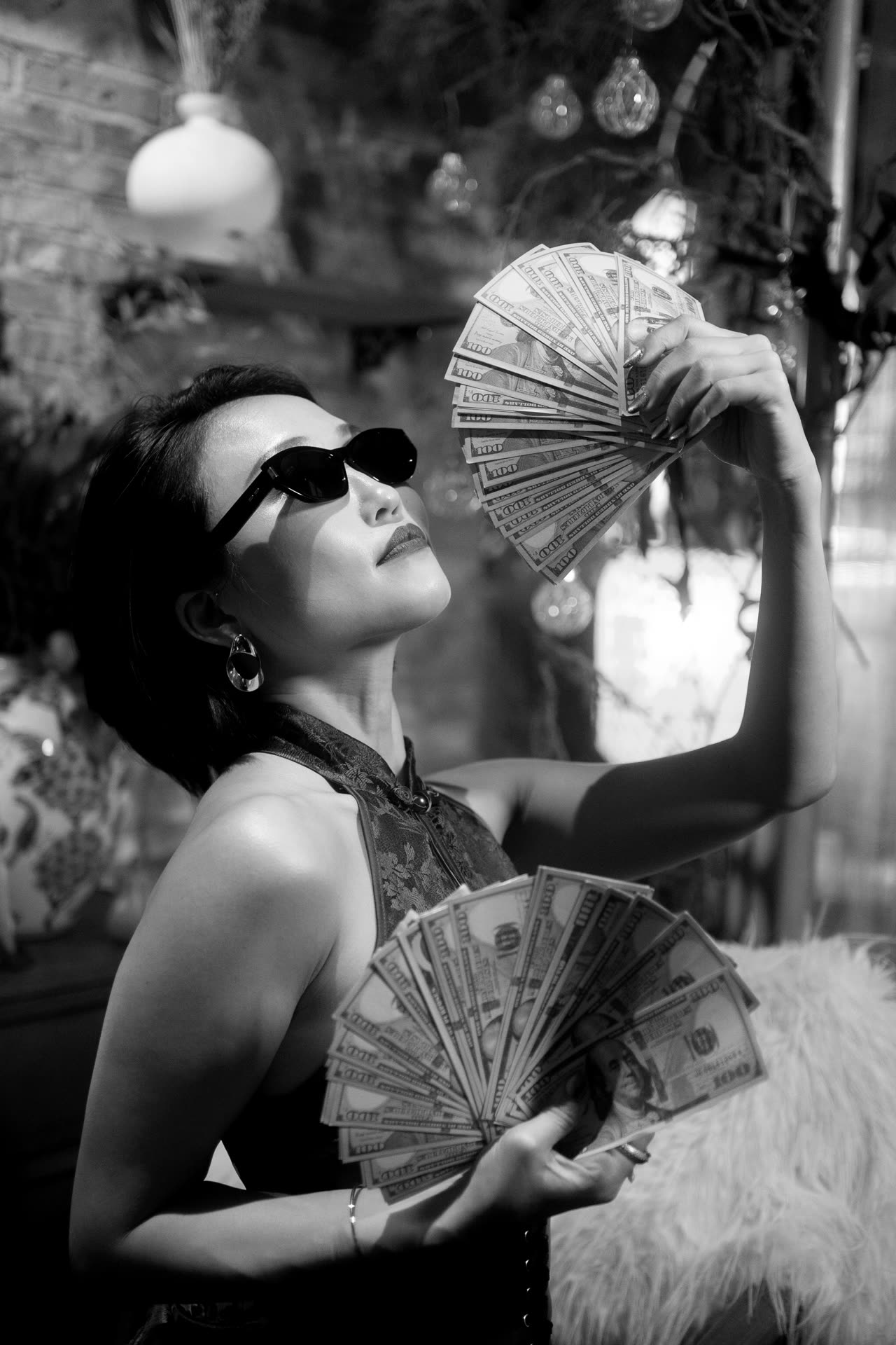 Crystal Chow in black and white, holding fans of hundred-dollar notes